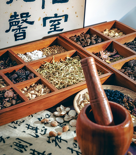 Herbalist measuring dried Chinese herbs on small brass scale