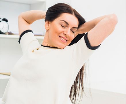 Person holding lower back with both hands while standing outdoors