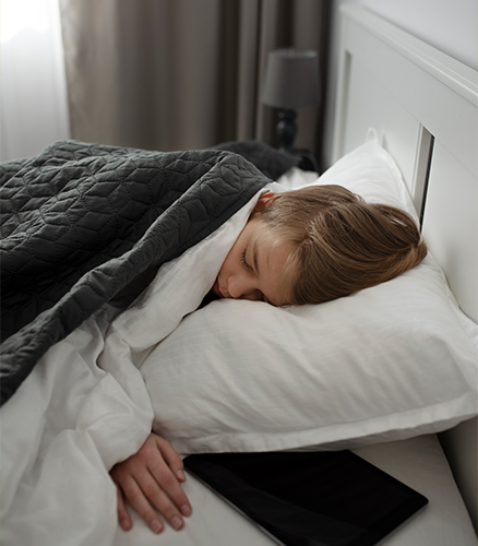 Hand reaching to turn off bedside lamp next to unmade bed