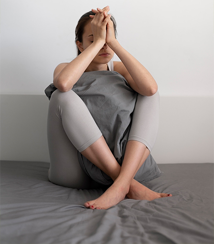 Woman practicing deep breathing while seated near bright apartment window